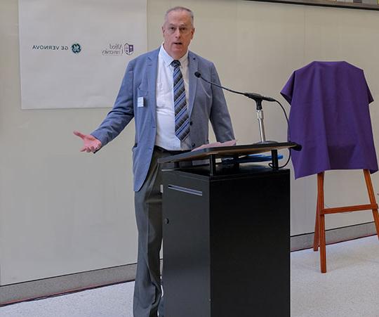 man talking at ribbon-cutting ceremony for new power grid training lab