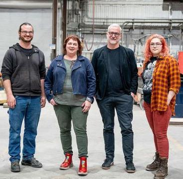 four people standing next to each other in a foundry